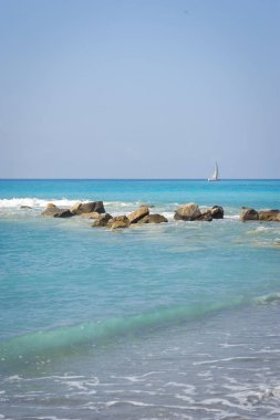 Deniz manzarası. Turkuaz su ile Ligurya Denizi kıyısında. Ufukta yelkenli.