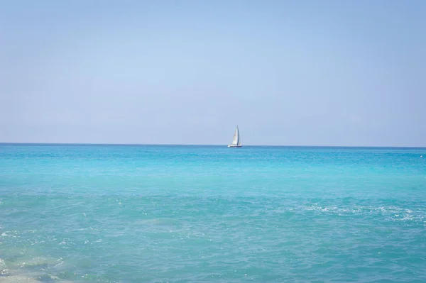 Zeegezicht. De kust van de Ligurische Zee, met turquoise water. Zeilboot op de horizon. — Stockfoto