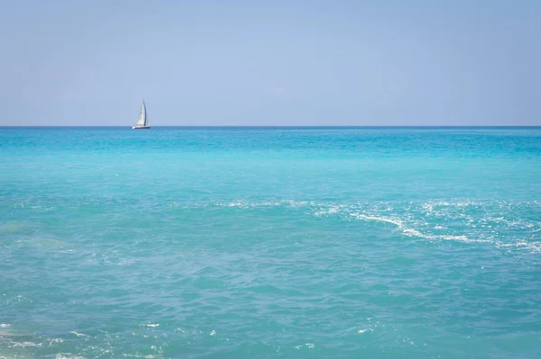 Paisaje marino. La costa del Mar de Liguria, con agua turquesa. Velero en el horizonte . Imagen de stock