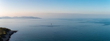 Mavi deniz ve gökyüzünün geniş bir kesiminin olduğu arkaplan fotoğrafı. Dağlar daha geride dizilmişti..