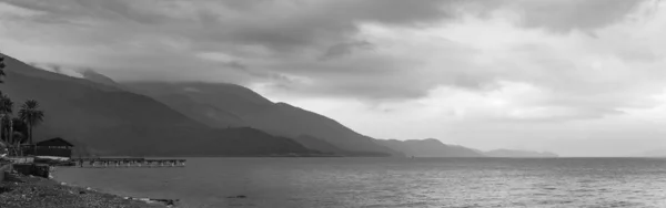 A gloomy sky over the sea as a background. Panoramic sea view suitable for dramatic works. Black and white high-resolution photo.