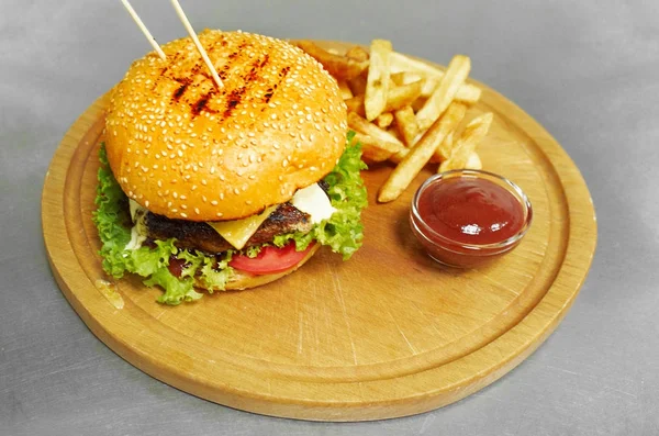Smaczny burger i frytki na drewnianym stole — Zdjęcie stockowe