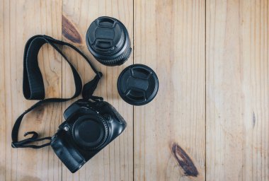 «Ana sayfa» seyahat nesnesinin görünümünü: siyah kamera ve ahşap masa üzerinde iki lens