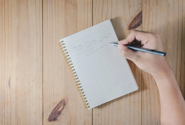 Adamın elini ahşap masa üstünde beyaz defter üzerinde 