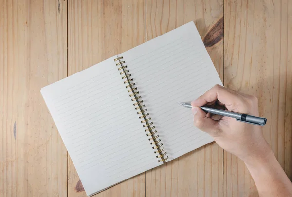Mano del hombre utilice la escritura del lápiz en el cuaderno blanco en la mesa de madera Imágenes De Stock Sin Royalties Gratis