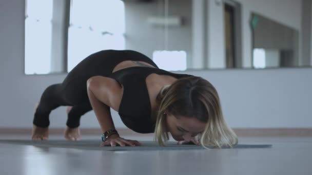 Ung kvinna värmer upp och gör några armhävningar en gymmet — Stockvideo