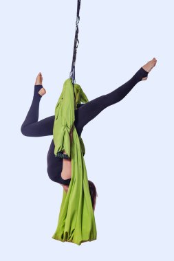 Genç kadın yeşil hamakta hava yoga yaparken.