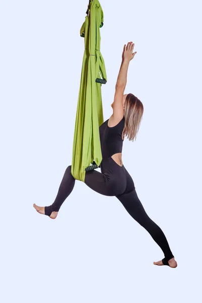 Молода жінка робить повітряну йогу в зеленому гамаку . — стокове фото