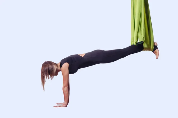 Young woman doing aerial yoga in green hammock.