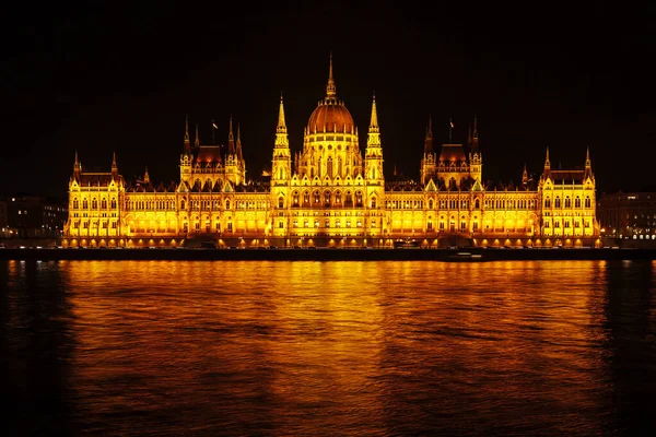 A Parlament épületének éjszakai kilátása Budapesten. Gyönyörű világítás és elmélkedés a Dunában. — Stock Fotó