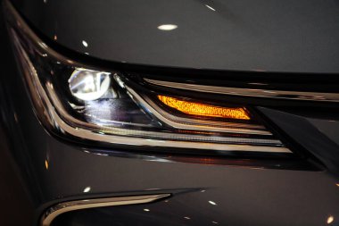 Bir arabanın farına yakın çekim. Pahalı bir araba galerisinin farları..