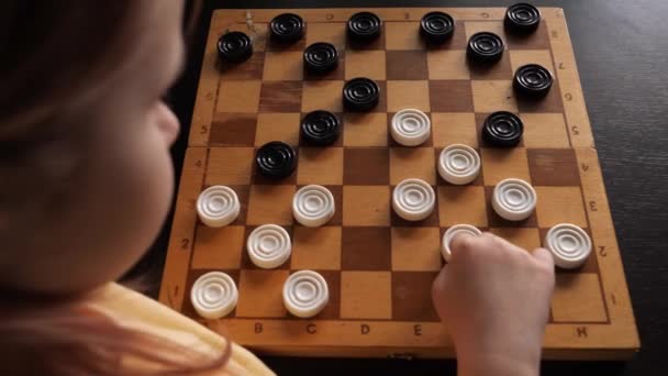 A little girl plays checkers with herself. A child plays board games at home. — Stock Video
