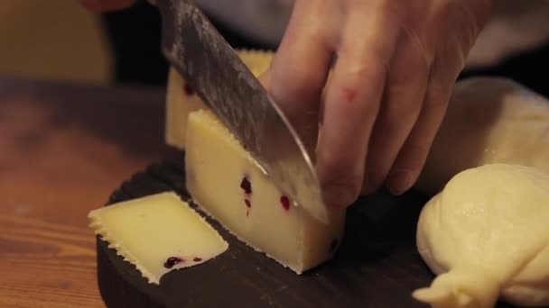 En kock skär ost på en svart skärbräda. — Stockvideo