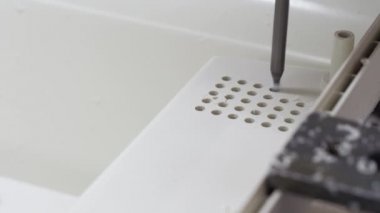 Makine plastik bir parçada delikler açar..