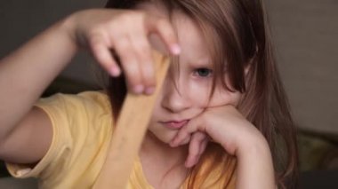 Küçük bir kız masada oturur ve sıkılır..