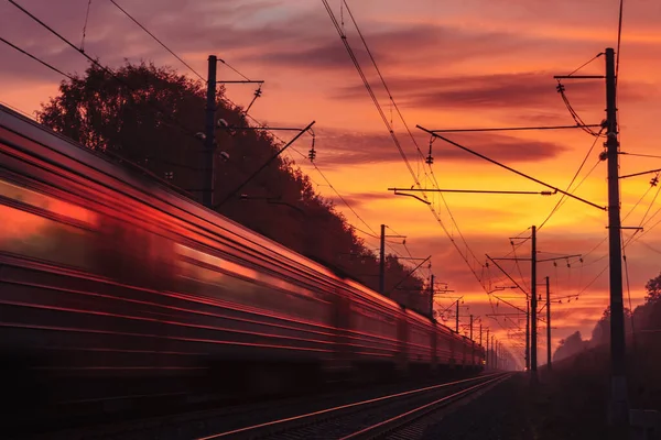 Поезд быстро движется вдаль под ярким закатным небом . Лицензионные Стоковые Фото