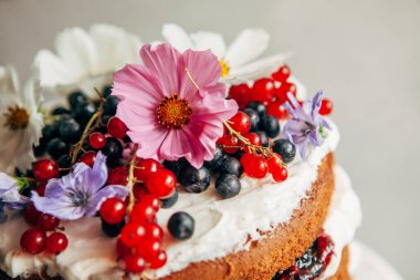 Çiçekler ve böğürtlenlerle süslenmiş bir pastanın yakın çekimi.