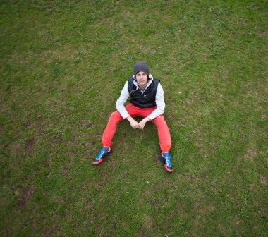 Sonbaharın kırmızı pantolon ile çimlerde oturan adam