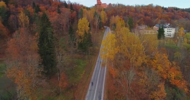 Conducir coche negro en la carretera en Sigulda. puente, camino de otoño, vuelo con drones, bosque amarillo — Vídeo de stock