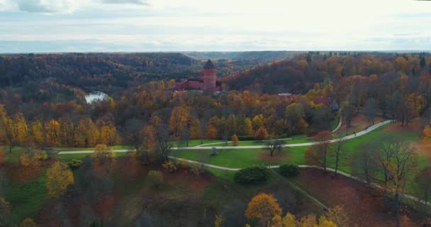 Castillo de Turaides Bosque de otoño Sigulda naturaleza de la ciudad, vuelo del dron del río Gauya, coche puente en coche desde arriba — Vídeos de Stock