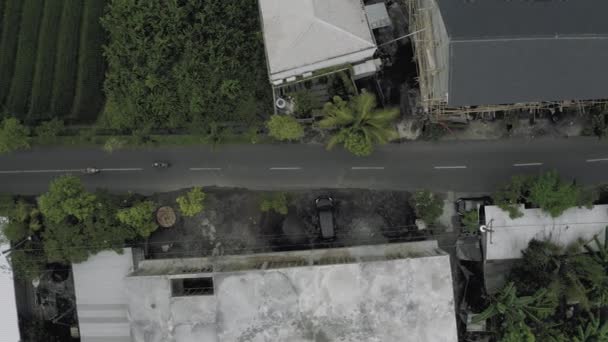 Autos und Fahrräder auf der Straße in der Stadt Canggu bali island 4k Drohnenflug — Stockvideo