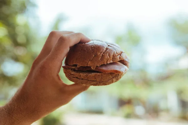 Вкусный сэндвич с ветчиной и салатом в руке — стоковое фото