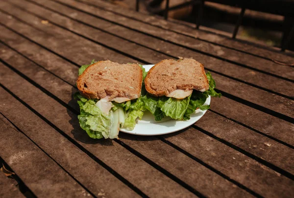 Sandwich con zumbido y ensalada en un banco de madera — Foto de Stock