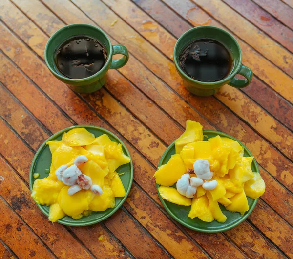 Горячий чай, свежий манго, мангостин и мандарины на деревянном столе — стоковое фото