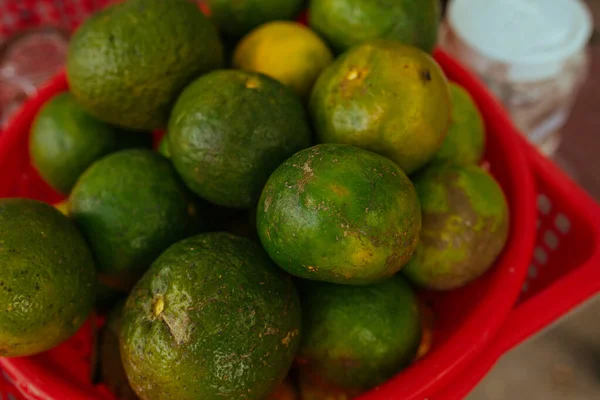 Gröna lime i en röd plastkorg — Stockfoto