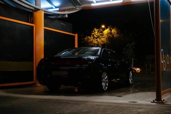 Myjnia samochodowa noc czarny samochód i oświetlenie lampy — Zdjęcie stockowe