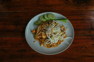 Tavuklu Tayland eriştesi, salatalık ve ahşap masada bambu çubukları.