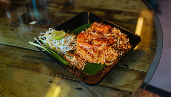 Almohadilla de fideos tailandeses con mariscos y nueces en la mesa — Foto de Stock