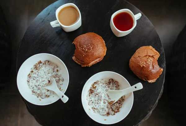 Snídaně, hamburger, čaj a káva na černém stole — Stock fotografie