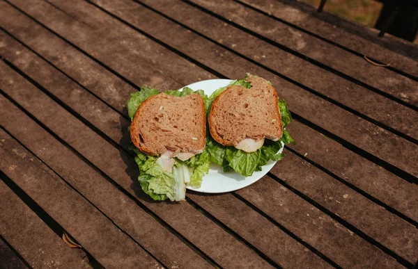 Sandwich con zumbido y ensalada en un banco de madera — Foto de Stock