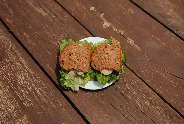Szendvics zümmögéssel és saláta egy fa padon — Stock Fotó