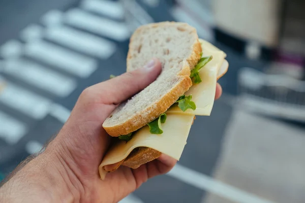 Kanapka z białym chlebem z szumem i sałatką w ręku człowieka w Monako — Zdjęcie stockowe