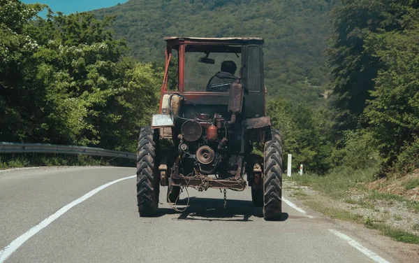 Старый трактор на дороге в горах Грузии Стоковая Картинка