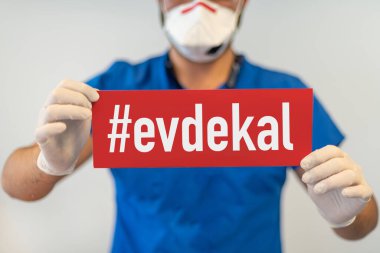 Elinde Eve Kal (Türkçe - İngilizce çevirisi: evde kal) olan bir doktor elinde tutarak Coronavirus veya Covid-19 salgınından korur.