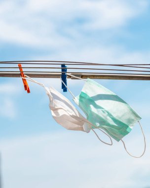 Korumalı tıbbi maske, Covid-19 koronavirüs pandemik karantinası sırasında çamaşır ipine asılmış.