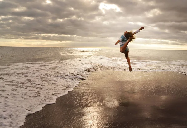 Gymnast in jump in ocean weaves.