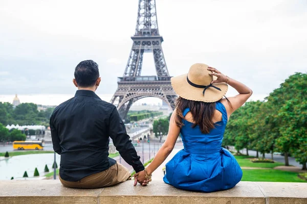 Luna de miel - Pareja joven de turistas sentados frente a la torre Eiffel en París Imágenes de stock libres de derechos
