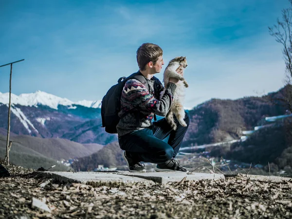 tourist with backpack playing with the cat on the mountain