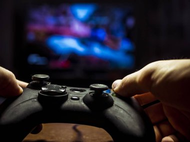 bir denetleyici holding ve t önünde bir video oyunu oynayan genç