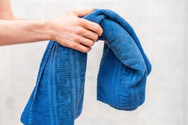 Bir insan banyo yapmadan önce renk havlusu tutar.