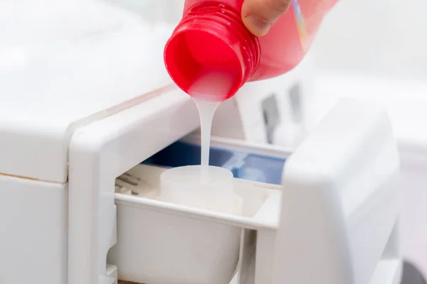 Pouring the washing conditioner in the washing machine to get clean cloth — Stock Photo, Image