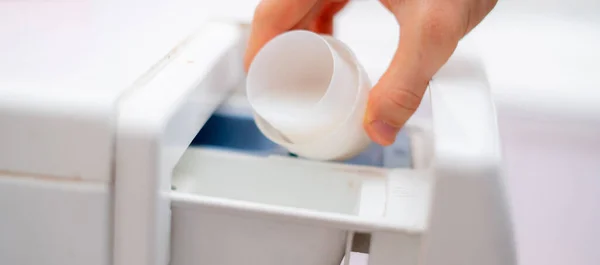 Pouring the washing conditioner in the washing machine to get clean cloth — Stock Photo, Image