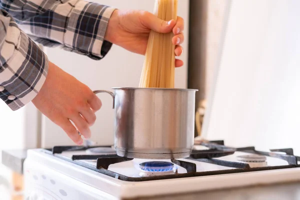 Mains mettre le bouquet de pâtes spaghetti dans la casserole dans la cuisine — Photo