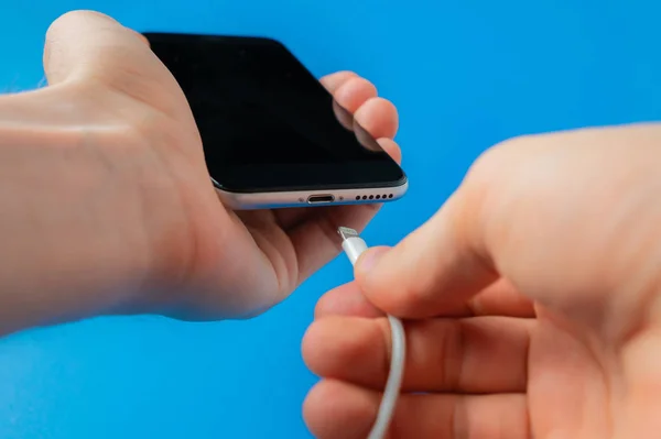 Ruce drží smartphone a nabíjecí drát, nízká baterie — Stock fotografie