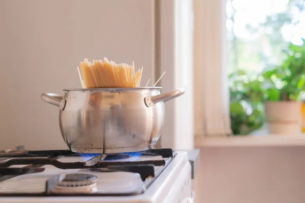 Las manos ponen el manojo de pasta de espagueti en la sartén en la cocina — Foto de Stock