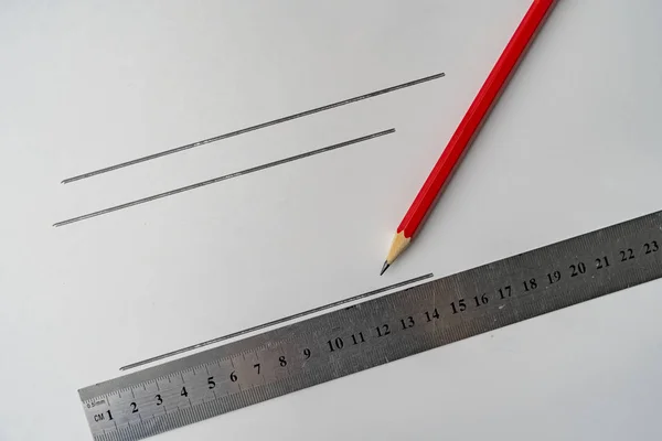 drawing a line on a color surface with a ruler and pencil